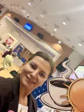 Dr Beata J. Kowalczyk z symbolami konferencji filiżanką kawy i słoneczkiem